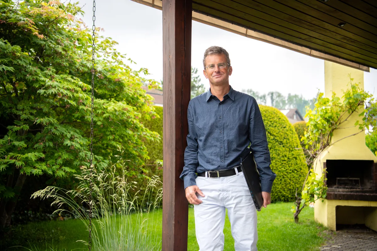 Thomas Renggli wurde vor Ablauf seines befristeten Arbeitsvertrags krankgeschrieben. (Archiv) Ein Mann in blauem Hemd steht angelehnt an eine Holzsäule.